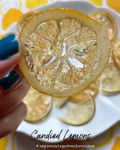 a hand holding a piece of lemon on top of a plate with gold coins in the background