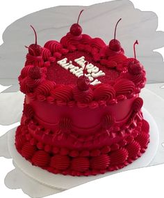 a red cake with white letters and cherries on it