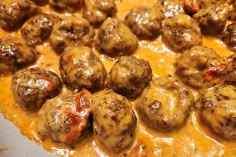 some meatballs are covered in cheese and sauce