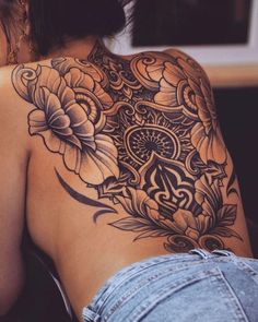 the back of a woman's shoulder with flowers on it and an ornamental design