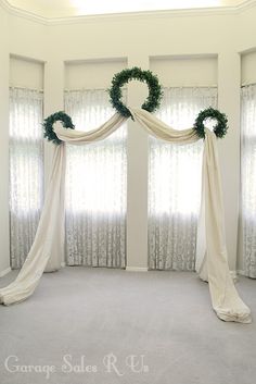 an empty room with curtains and wreaths on the windowsill