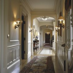 the hallway is lined with antique rugs and sconces, along with two lamps on either side of the door