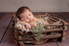 a newborn baby is sleeping in a basket made out of wood sticks and burlap