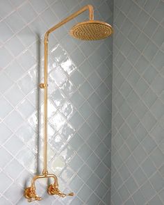 a gold shower head in a bathroom with blue walls and white tiles on the wall