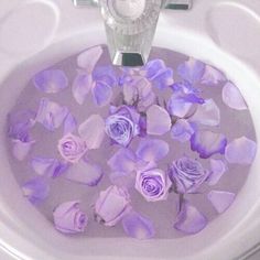 purple flowers floating in a white bowl filled with water on top of a toilet seat