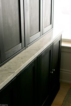 a kitchen with black cabinets and marble counter tops