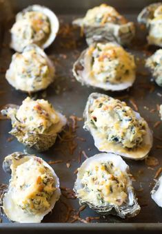 several oysters with cheese and other toppings on a baking sheet