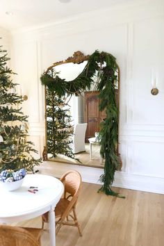 a christmas tree in the corner of a room with a mirror and chair next to it