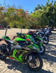 a row of motorcycles parked next to each other on a brick road with trees in the background