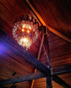 a chandelier hanging from the ceiling in a room with wooden walls and beams