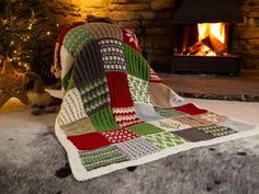 a blanket that is on the ground next to a fire place with a christmas tree