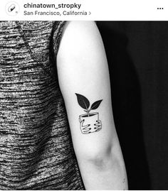 a black and white photo of a person with a plant in a cup on their arm