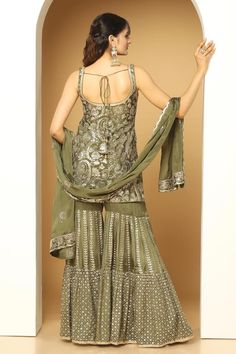 Olive green sleeveless padded short kurta in chinon chiffon base with all over sequin paisley fleur embroidery and paan neckline. Paired with a vine and floral jaal embellished sharara and embroidered border dupatta. - Aza Fashions Sleeveless Chinon Dresses For Eid, Traditional Sleeveless Chinon Dress, Sleeveless Georgette Salwar Kameez With Mirror Work, Fitted Green Chinon Palazzo Set, Sleeveless Chinon Dress With Mirror Work, Sleeveless Chinon Dress With Dupatta, Sleeveless Georgette Sharara With Mirror Work, Fitted Sleeveless Georgette Salwar Kameez, Festive Sleeveless Chinon Sharara