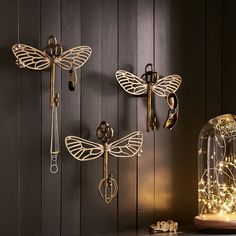 three dragonflys are hanging on the wall next to a clock and some lights