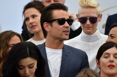 a group of people standing next to each other in front of a man wearing sunglasses