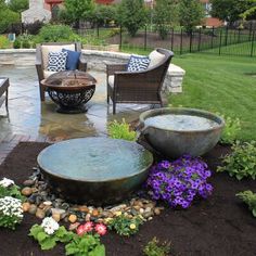 an outdoor living area with chairs, table and water feature