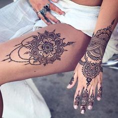 a woman's legs with henna tattoos on them and her hand resting on the leg