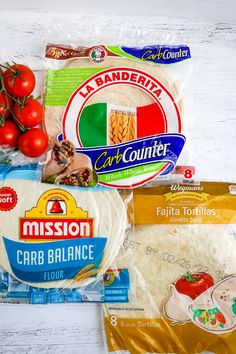 the ingredients for this meal are laid out on a white wooden surface, including tomatoes, cheese, pasta and bread