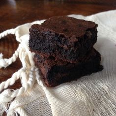 two pieces of brownie sitting on top of a white cloth next to a wooden table