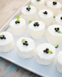 small desserts with black olives on top are arranged on a metal tray, ready to be eaten