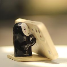 a black and white cat figurine sitting on top of a wooden board with two buttons