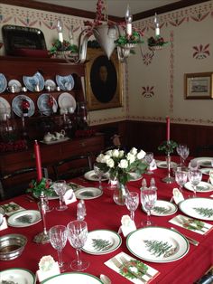 the table is set for christmas dinner with red linens and green trimmings