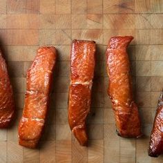 four raw salmons are lined up on a cutting board, ready to be cooked