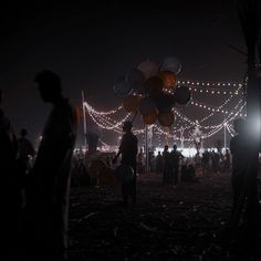 many people are standing around with balloons in the dark