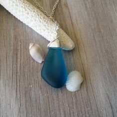 a necklace with two seashells hanging from it's side on a wooden surface