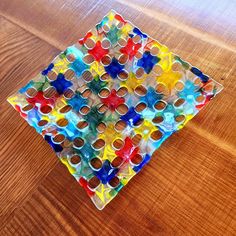 a colorful glass plate sitting on top of a wooden table covered in lots of different colored cups