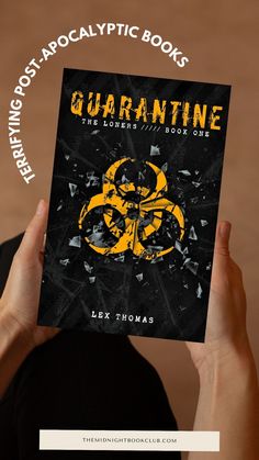 a person holding up a book with the title quarantine in front of them