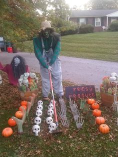 a scarecrow is holding a broom in front of pumpkins and other decorations on the lawn