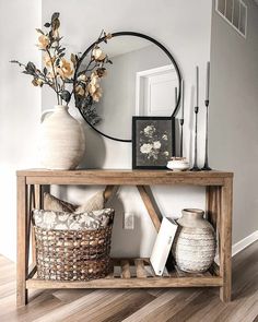 a wooden table topped with a mirror next to a vase filled with flowers and other items