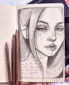 an open notebook with a drawing of a woman's face on it and two pencils next to it