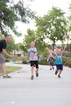 a group of young children playing with a frisbee on a sidewalk in the park