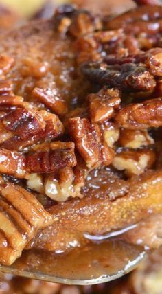 a spoon with pecans on top of some kind of food that is being eaten