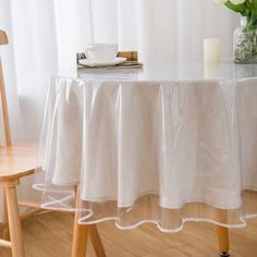 a table with a white cloth on it next to a wooden chair and vase filled with flowers