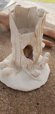 a white vase sitting on top of a table next to a tree stump and an open book