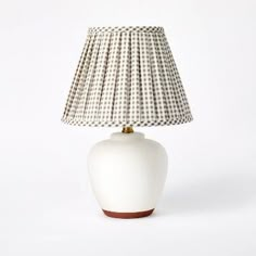 a white table lamp with a brown base and a beige shade on the top, against a white background