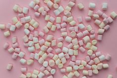 marshmallows are scattered on a pink surface