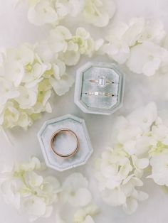 two wedding rings sitting next to each other in front of white flowers