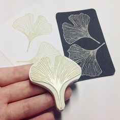 a hand holding a rubber stamp that has two leaves on it, and one is in the shape of a leaf