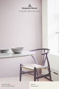 a white table with two bowls on it and a purple chair in front of the window