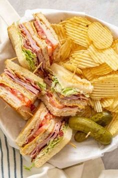 a club sandwich with chips and pickles on the side