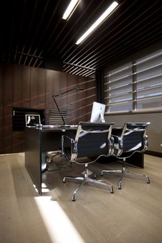 an empty office with two chairs and a desk in the middle is lit by sunlight