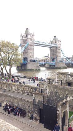 people are sitting on benches in front of the tower bridge