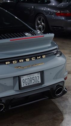 the back end of a grey porsche parked in a garage with other cars behind it