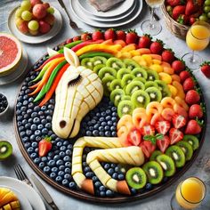 a horse made out of fruits and vegetables on a plate next to plates with fruit