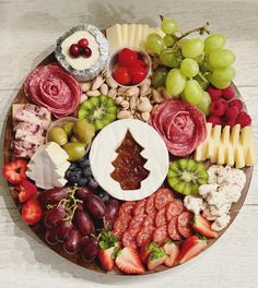 a platter filled with fruit, cheese and meats on top of a wooden table