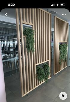 three wooden partitions with plants growing on them in an office building lobby, along with tables and chairs